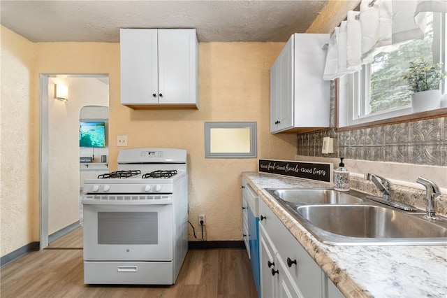 kitchen featuring white cabinetry, sink, light hardwood / wood-style floors, and white gas range oven