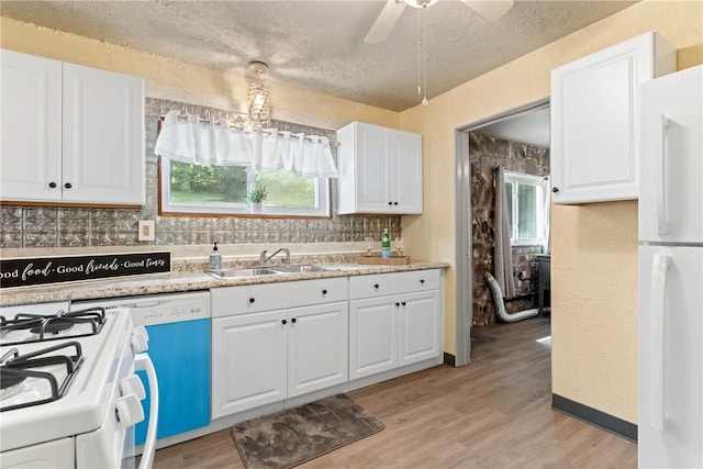 kitchen with sink, white appliances, light hardwood / wood-style floors, decorative backsplash, and white cabinets