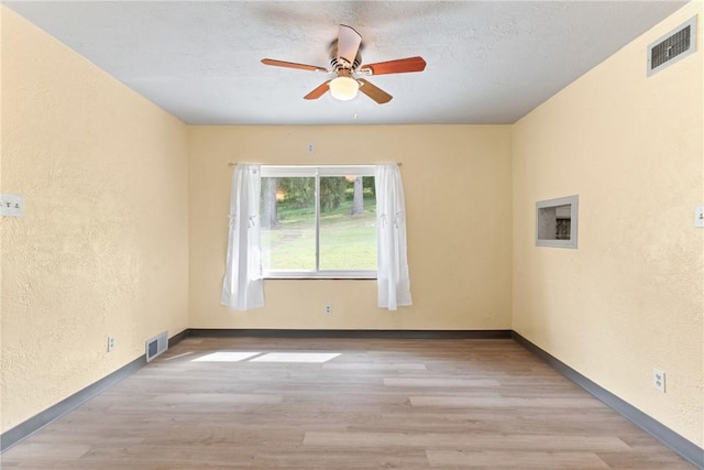 empty room featuring ceiling fan, a textured ceiling, and light hardwood / wood-style floors