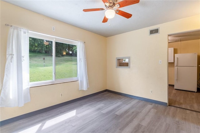 spare room with ceiling fan and light wood-type flooring