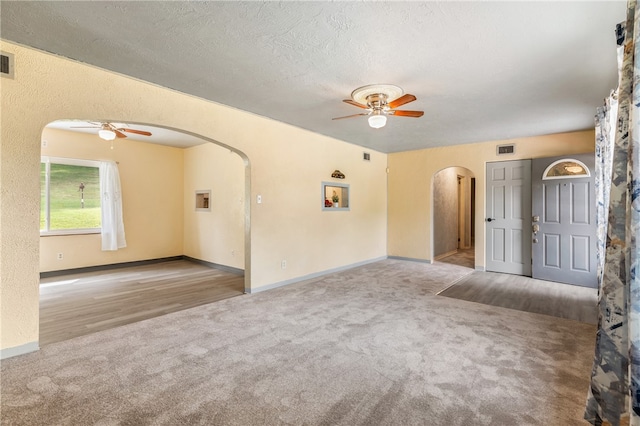 unfurnished room with light colored carpet, a textured ceiling, and ceiling fan