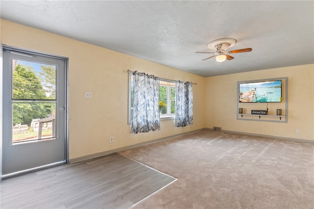 carpeted spare room with ceiling fan and a textured ceiling