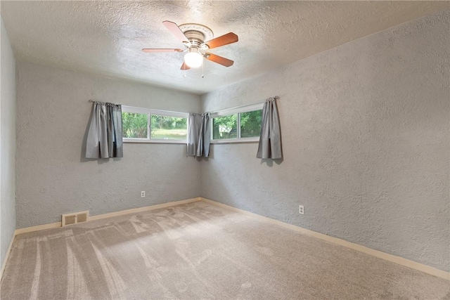 empty room with ceiling fan, carpet floors, and a textured ceiling