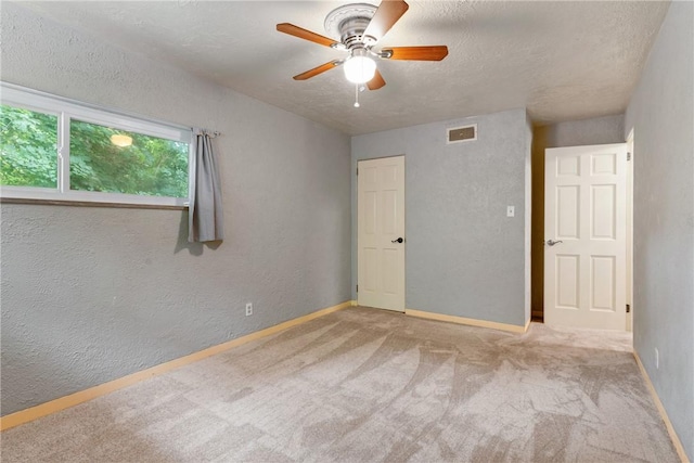 carpeted empty room with ceiling fan and a textured ceiling