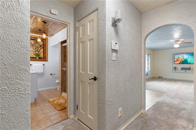 hallway with a textured ceiling and carpet flooring