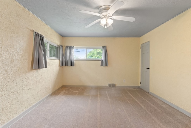 carpeted empty room with ceiling fan and a textured ceiling