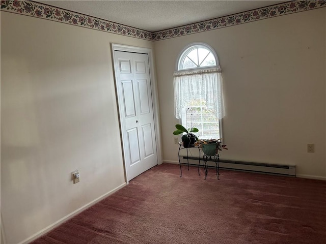 empty room featuring dark colored carpet, a baseboard radiator, and a textured ceiling