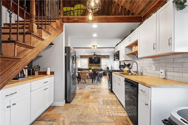 kitchen featuring pendant lighting, black appliances, sink, and white cabinets