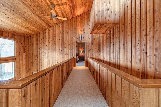 hallway featuring wood ceiling, vaulted ceiling, light colored carpet, and wooden walls