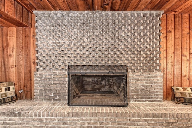 interior details featuring wood walls, a brick fireplace, and wooden ceiling