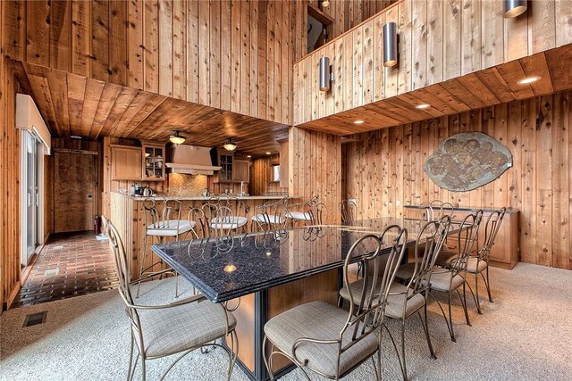 bar with carpet floors, wooden walls, wooden ceiling, and stone countertops