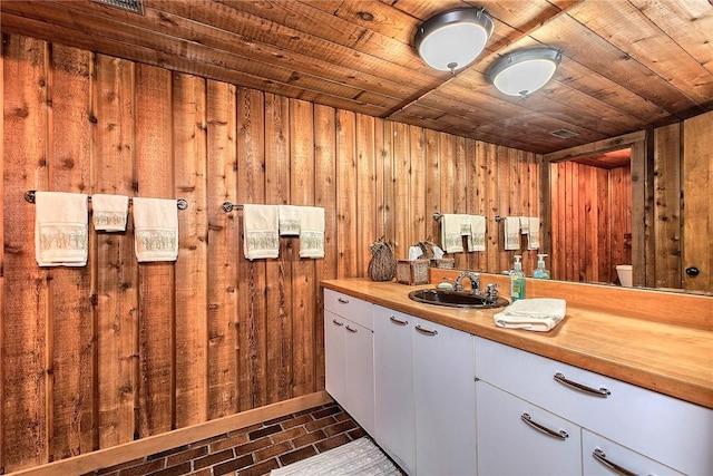 bathroom with toilet, vanity, wooden walls, and wooden ceiling