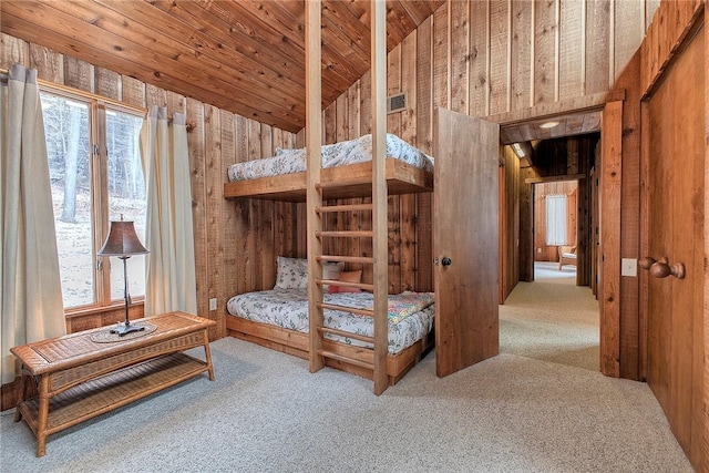 carpeted bedroom featuring wooden walls, vaulted ceiling, multiple windows, and wooden ceiling