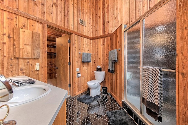 bathroom with toilet, vanity, wooden walls, and walk in shower