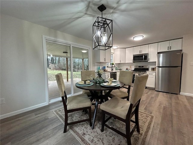 dining space with hardwood / wood-style floors, a notable chandelier, and sink