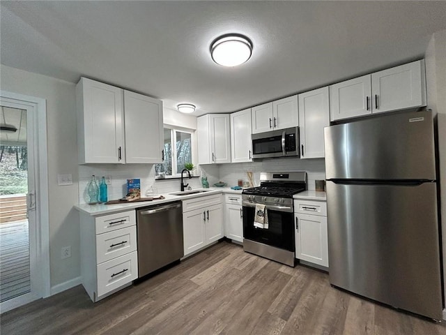 kitchen featuring sink, dark wood-type flooring, appliances with stainless steel finishes, white cabinetry, and backsplash