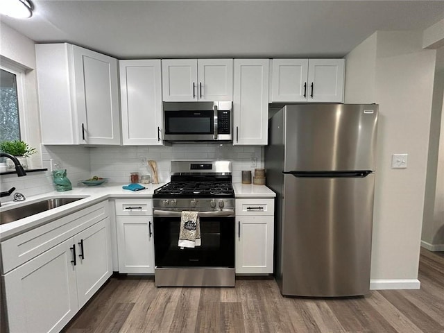 kitchen featuring sink, tasteful backsplash, wood-type flooring, appliances with stainless steel finishes, and white cabinets