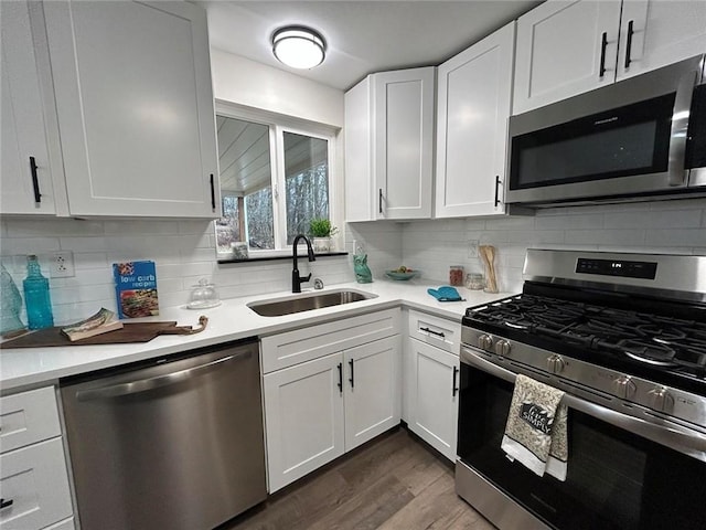 kitchen with dark hardwood / wood-style floors, sink, white cabinets, decorative backsplash, and stainless steel appliances