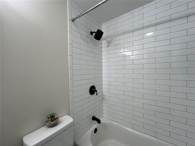 bathroom featuring toilet and tiled shower / bath