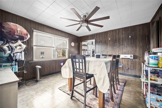 dining space featuring wooden walls and ceiling fan