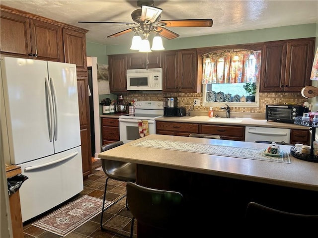 kitchen featuring sink, white appliances, dark tile patterned floors, ceiling fan, and backsplash