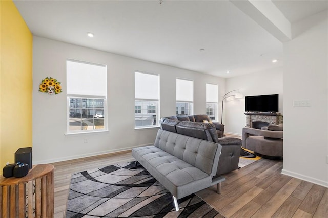 living room with a stone fireplace and light wood-type flooring