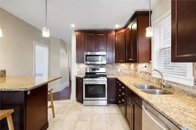 kitchen featuring stainless steel appliances, sink, pendant lighting, and a kitchen bar