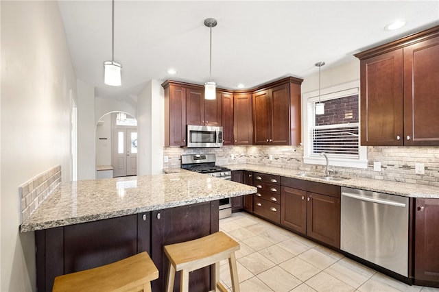 kitchen with stainless steel appliances, a breakfast bar, pendant lighting, and kitchen peninsula