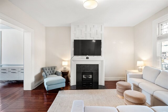 living room with a tile fireplace and dark hardwood / wood-style flooring