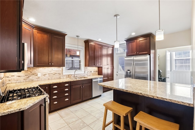 kitchen featuring sink, a breakfast bar, appliances with stainless steel finishes, hanging light fixtures, and decorative backsplash