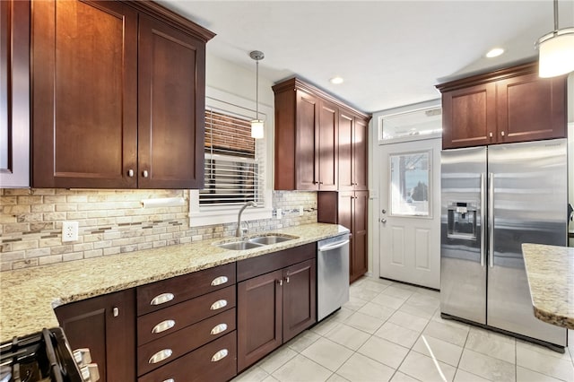 kitchen featuring sink, decorative backsplash, hanging light fixtures, light stone counters, and stainless steel appliances