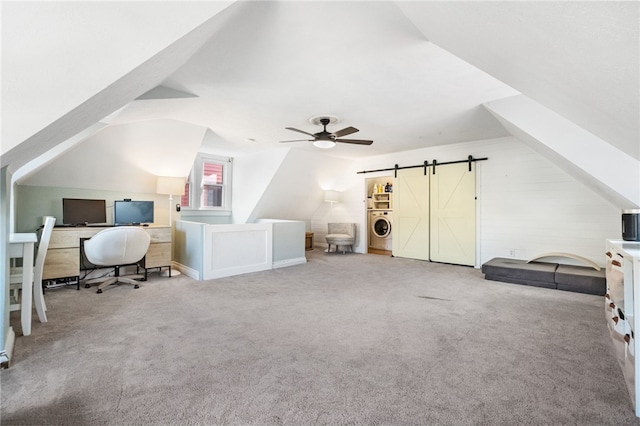 carpeted office space featuring a barn door, washer / dryer, lofted ceiling, and ceiling fan