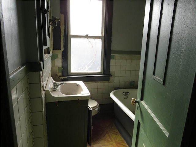 bathroom featuring tile walls, vanity, a bathtub, and toilet