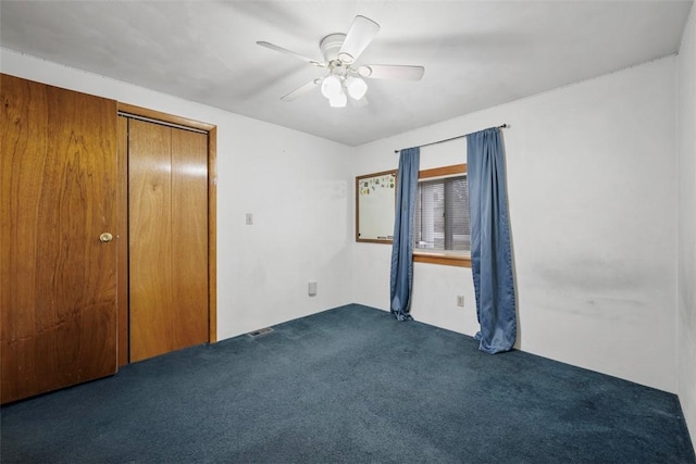 unfurnished bedroom with ceiling fan and dark carpet