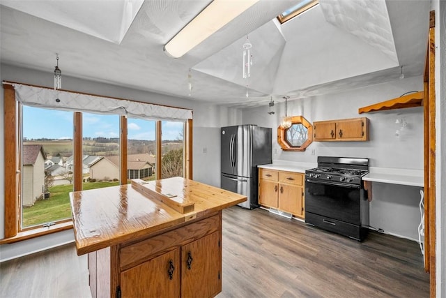 kitchen featuring a center island, black gas range oven, dark wood-type flooring, and stainless steel fridge