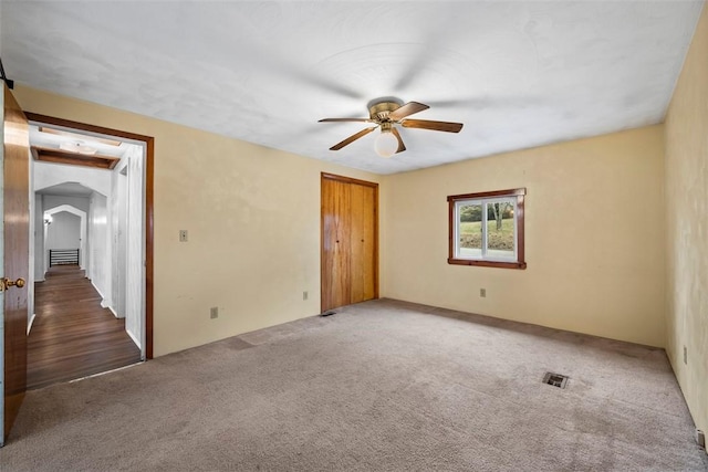 spare room with dark carpet and ceiling fan