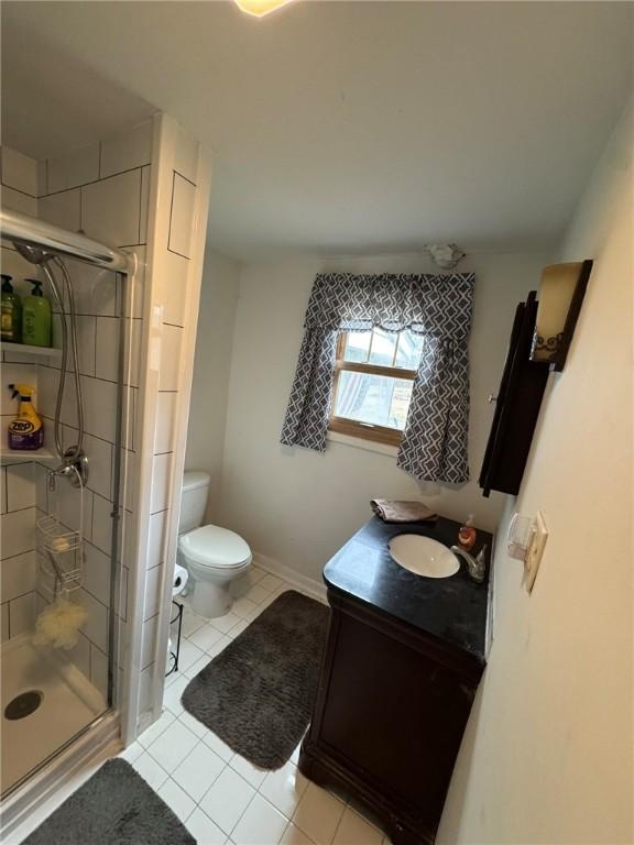 bathroom featuring a shower with door, vanity, tile patterned flooring, and toilet