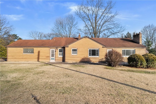 view of front facade with a chimney, a front lawn, and brick siding