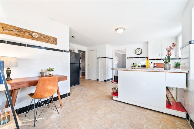 kitchen with light countertops, freestanding refrigerator, and white cabinets