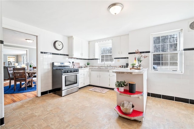 kitchen with light countertops, a sink, stainless steel gas range oven, and white cabinetry