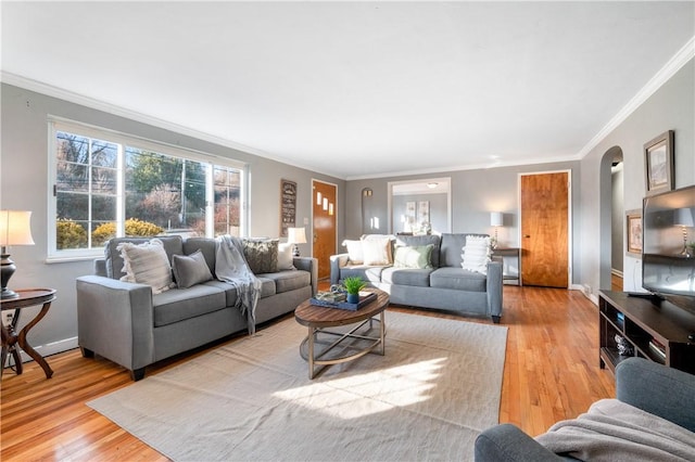 living area with light wood-style flooring, arched walkways, baseboards, and ornamental molding