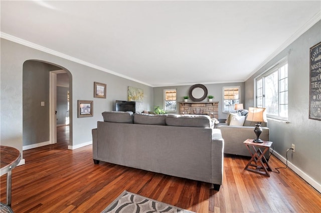 living room with baseboards, crown molding, arched walkways, and wood finished floors