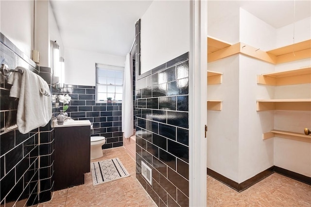 bathroom with tile patterned flooring, toilet, visible vents, tile walls, and a spacious closet