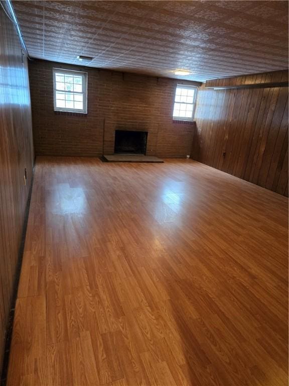 below grade area with brick wall, a fireplace, and wood finished floors