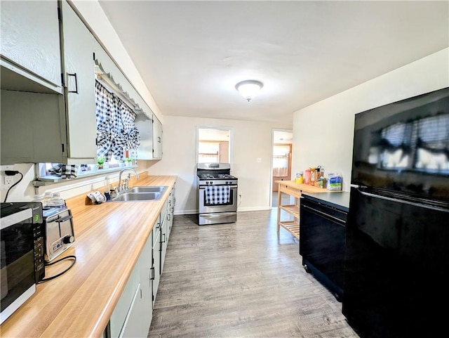 kitchen with white cabinetry, butcher block counters, sink, hardwood / wood-style flooring, and black appliances