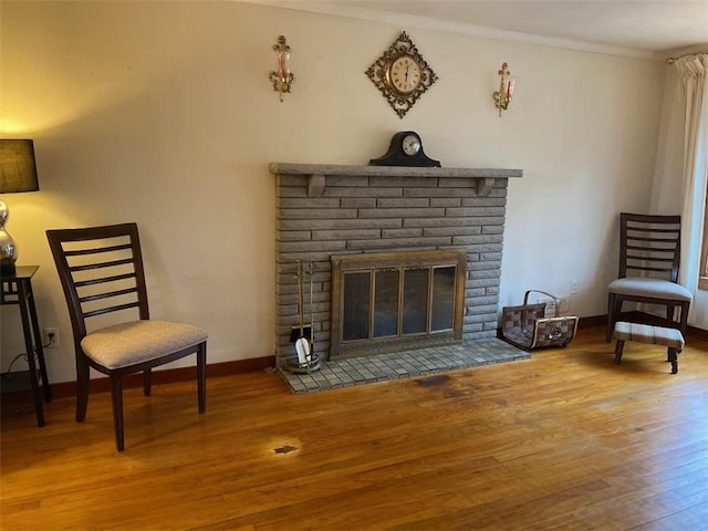 living area with ornamental molding, hardwood / wood-style floors, and a fireplace