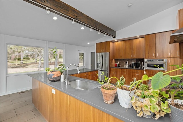 kitchen featuring sink, light tile patterned floors, stainless steel appliances, tasteful backsplash, and lofted ceiling with beams