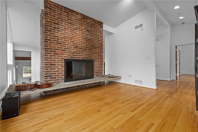 unfurnished living room with high vaulted ceiling, a fireplace, and light hardwood / wood-style floors