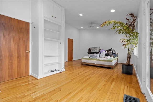 interior space with built in features, light hardwood / wood-style floors, and ceiling fan