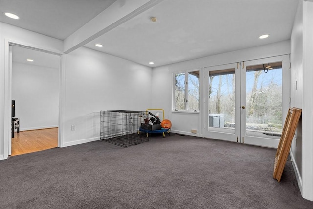 unfurnished room with beamed ceiling, dark carpet, and french doors